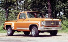 an orange and white truck parked in front of trees