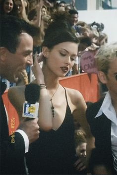 a woman in a black dress is surrounded by reporters