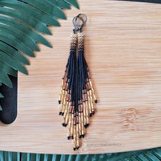 a wooden board with some beads hanging from it's end and a plant in the background