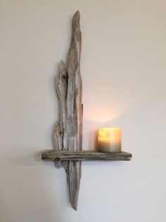 a candle is lit on a shelf made out of driftwood with a light in the corner