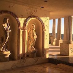 statues are lined up against the wall in an old building with columns and arches on either side