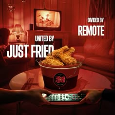 a bucket full of fried chicken sitting on top of a table next to a remote control