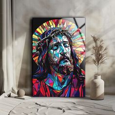 a painting of jesus on a wall next to a vase with a plant in it