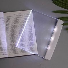 an open book sitting on top of a white table next to a green leafy plant