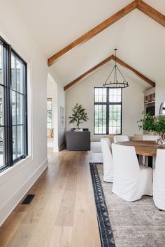 a dining room table and chairs in front of a large window with wood beams