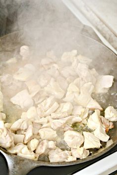 chicken is cooking in a wok on the stove