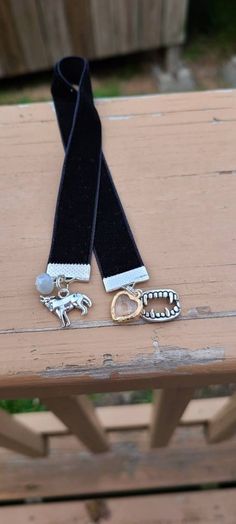 a pair of black and white leashes sitting on top of a wooden bench next to two silver rings