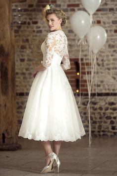 a woman in a white dress standing next to balloons