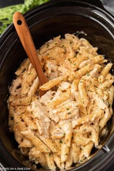 pasta in a crock pot with a wooden spoon