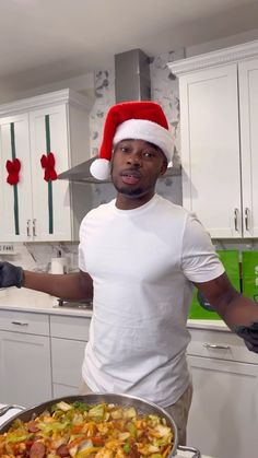 a man in a santa hat holding a pan of food