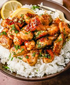 a plate full of chicken and rice with lemon wedges