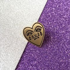 a close up of a heart shaped brooch on a purple and silver glitter background