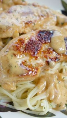 a pasta dish with chicken and gravy is shown on a white and black plate