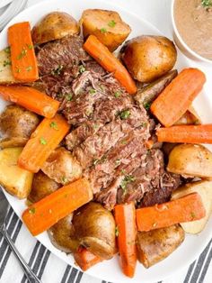 a white plate topped with roast, potatoes and carrots next to a bowl of dipping sauce