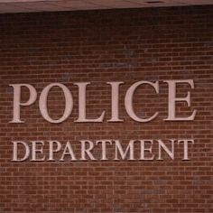 the police department sign is painted on a brick wall