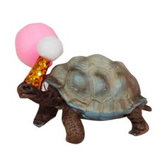 a small toy turtle with a pink balloon on its back and an orange cone stuck to it's shell