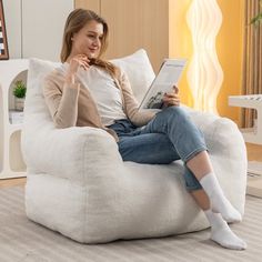 a woman sitting on a bean bag chair reading a book