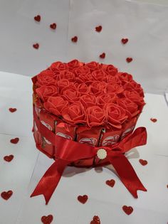 a heart shaped box filled with red roses on top of a white table covered in hearts