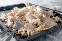 a tray filled with sliced chicken on top of a table next to utensils