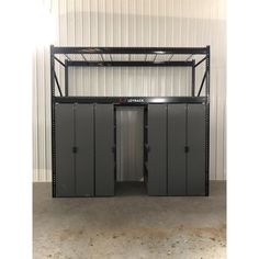 an empty metal storage unit with two doors and three stalls on the side, in front of a white wall