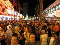 a large group of people standing in front of a building at night with lights on