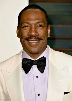 a close up of a person wearing a suit and bow tie