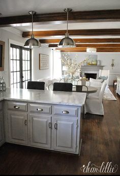 a kitchen with white cabinets and wood floors in the center, along with an island that has seating for four