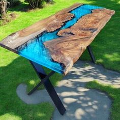 a wooden table sitting on top of a grass covered field next to a tree trunk