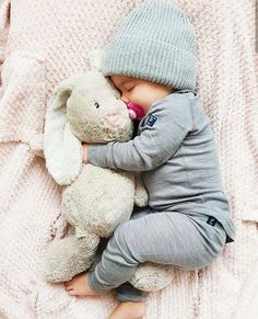 a baby is sleeping with a stuffed animal