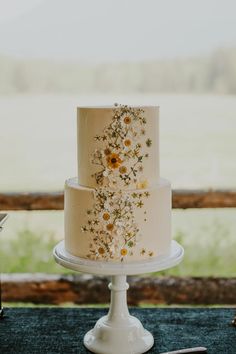 a three tiered cake with flowers on it sitting on top of a table next to a knife and fork