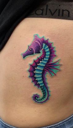 a colorful seahorse tattoo on the back of a woman's stomach