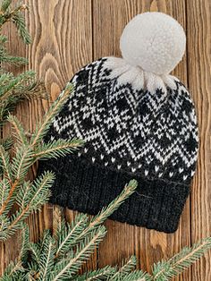 a black and white hat sitting on top of a wooden table next to pine branches