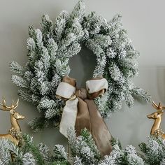 a christmas wreath with two deer figurines in front of it and one on the wall