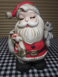 a santa clause figurine sitting on top of a black and white checkered table cloth