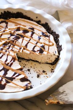 a pie with chocolate and caramel drizzled on top is sitting in a white dish