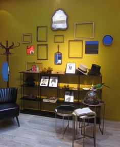 a living room with yellow walls and pictures on the wall, chairs and tables in front of it