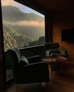 a living room filled with furniture and a large window covered in foggy mountains behind it