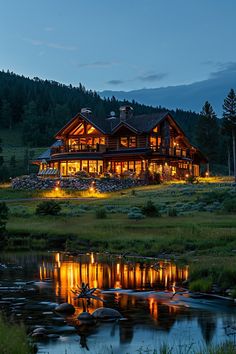 a log cabin lit up at night with the lights on and reflecting in the water