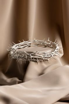 a crown of thorns sitting on top of a satin covered table cloth next to a curtain