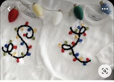 two knitted sweaters with christmas lights on them, one is white and the other is red