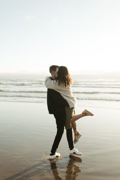 a man and woman hugging on the beach