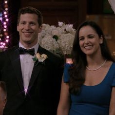 a man in a tuxedo standing next to a woman wearing a blue dress