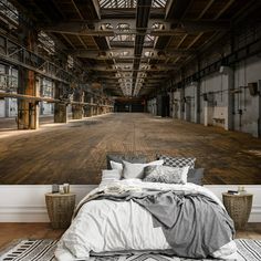 an empty warehouse with wooden floors and large bedspread on the floor, in front of a wall mural