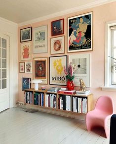 a living room filled with furniture and lots of framed pictures on the wall behind a bookshelf