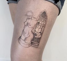 a woman's thigh with a tattoo of a teddy bear and a stained glass window