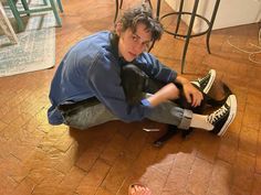 a young man sitting on the floor with his dog in front of him and looking at the camera