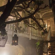 a lantern hanging from a tree in front of a building with stairs and railings