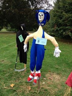 two mannequins dressed in costumes standing on grass