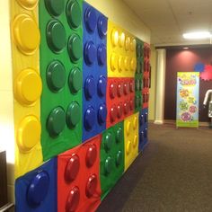 a wall made out of legos in an office building with children's artwork on the walls