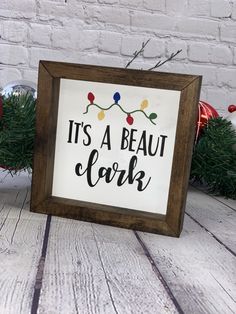 it's a beaut clark christmas sign on a wooden table with pine branches